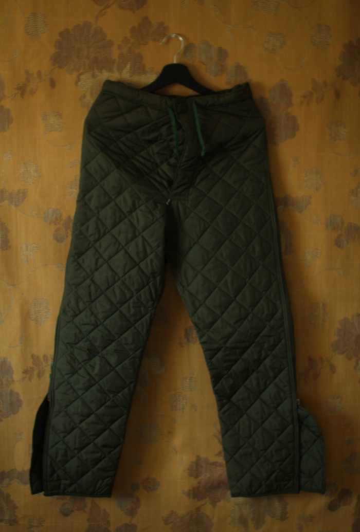 Vintage military surplus forest green quilted liner pants, front view on hanger